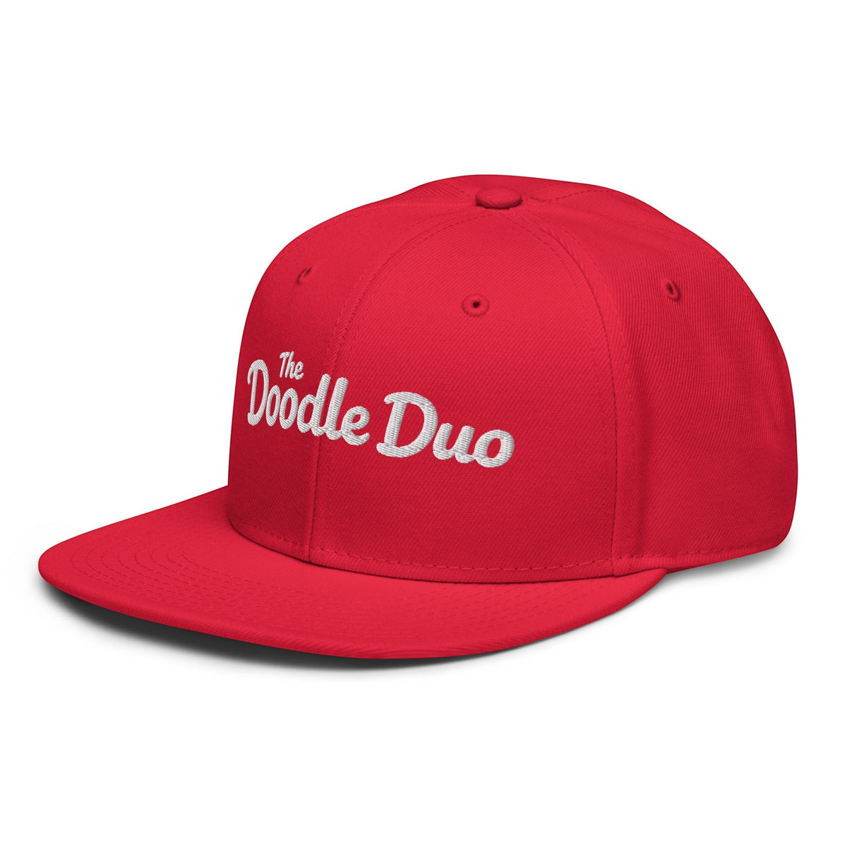 The Doodle Duo red snapback hat with white embroidered signature text and paw print on a structured 6-panel cap.